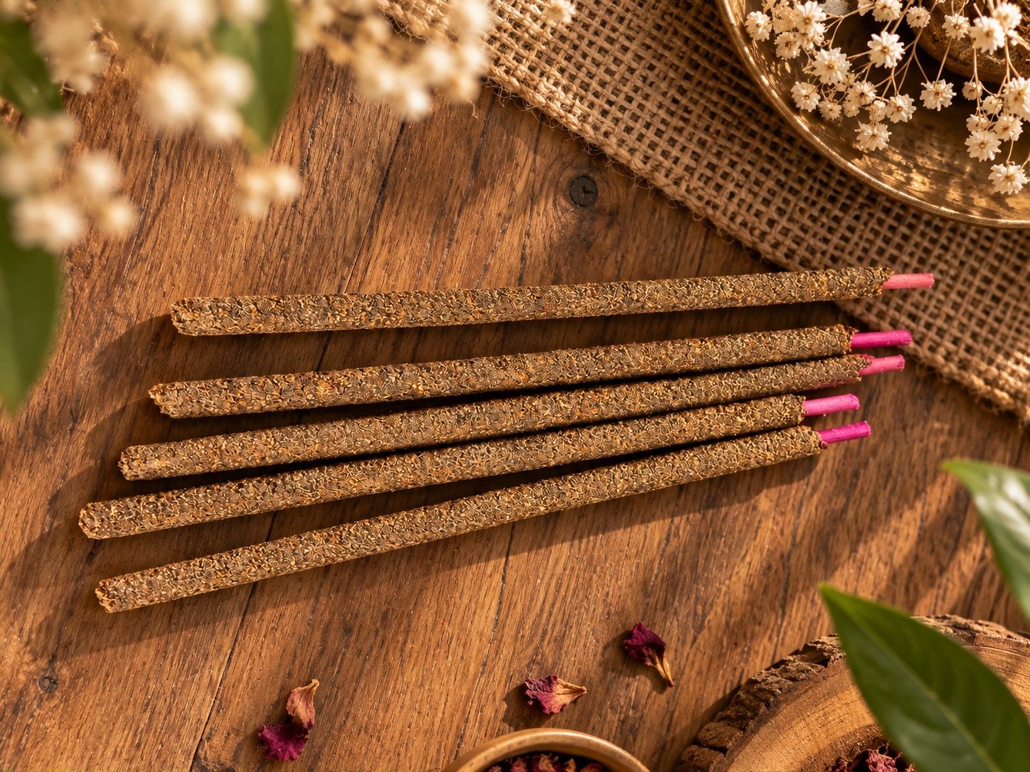 Hand-rolled aroma sticks on a wooden table among dried temple flowers
